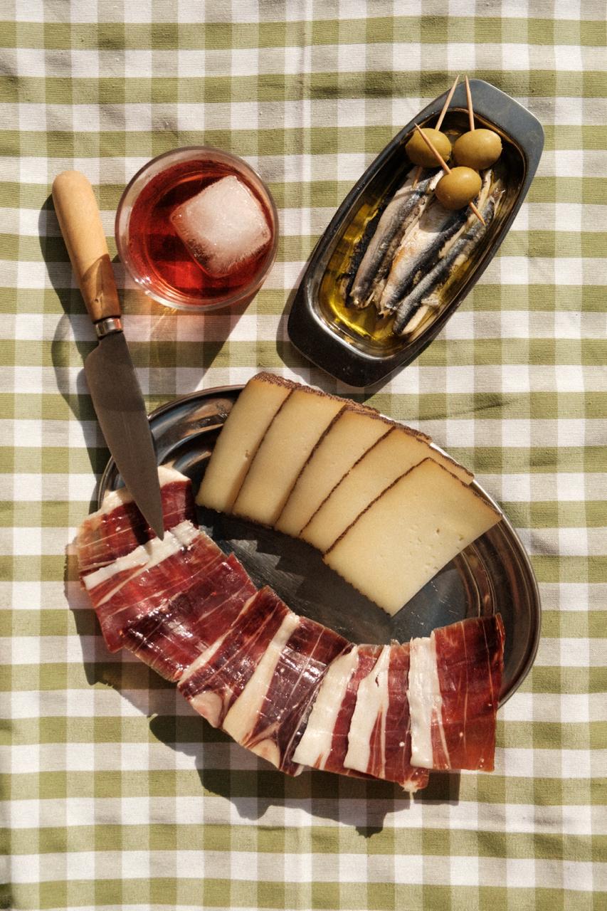 Au centre de l'image on voit le jamón de bellota 100% ibérico de la marque LOLO présenté avec un plateau de fromge.