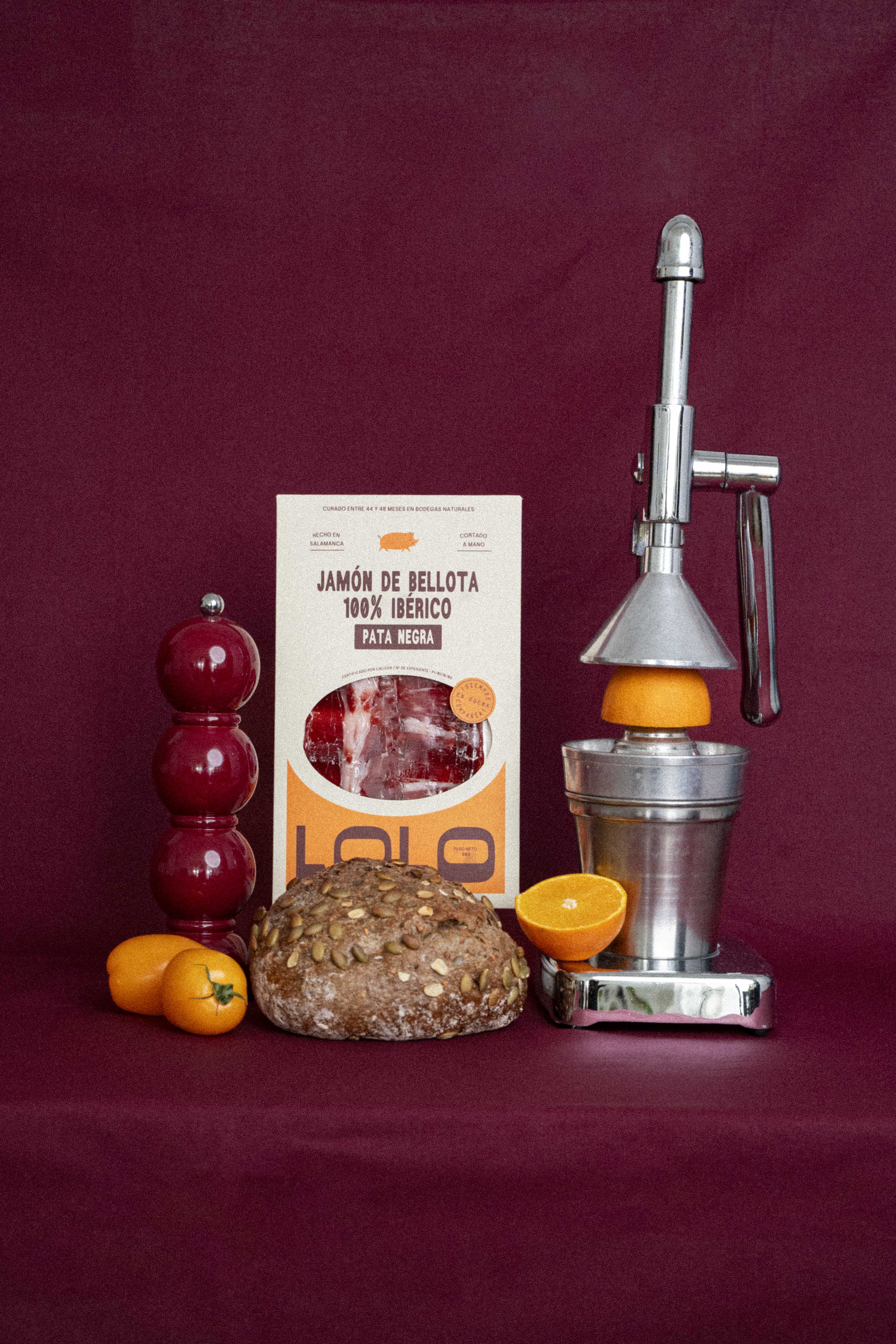 Un paquet de jambon 100% ibérique, coupé au couteau, dans un décor où le fond est bordeaux, avec des élèments de décoration