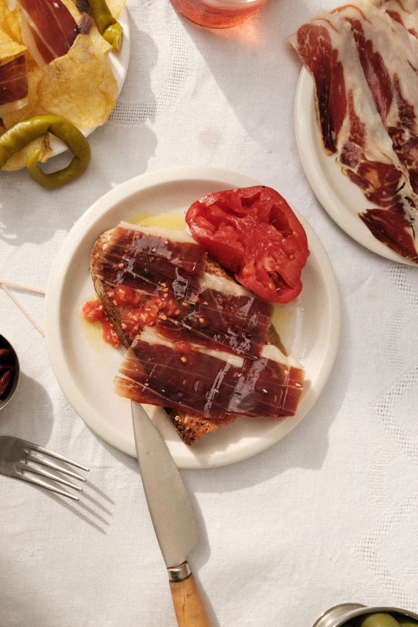 Pain à la tomate dans une assiette avec des tranches de jambon ibérique de bellota pata negra LOLO