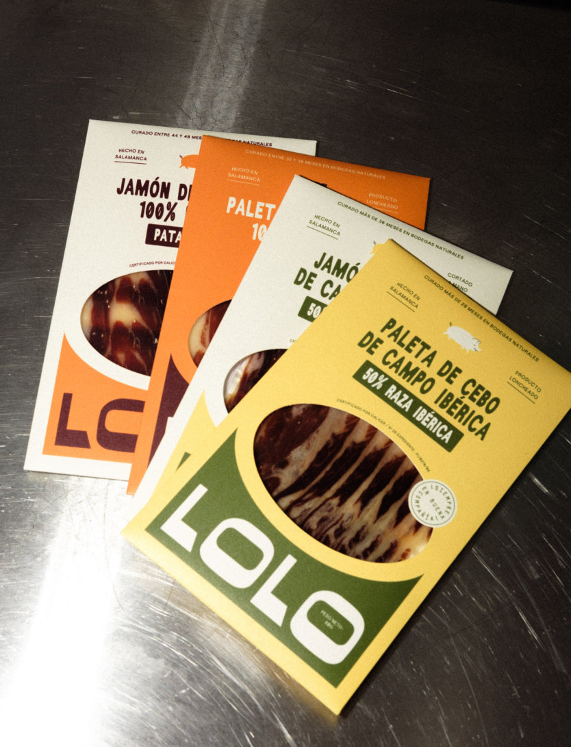 La gamme complète de la marque LOLO avec ses 4 produits sur une table : Paleta de cebo de campo 50% ibérique et Jamón de cebo de campo 50% ibérique mais aussi Paleta de bellota 100% ibérique pata negra et jamón de bellota 100% ibérique pata negra